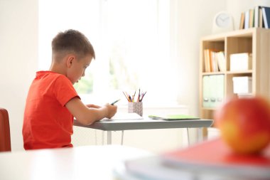 Sevimli küçük çocuk sınıfta masasında atama yapıyor. İlköğretim Okulu