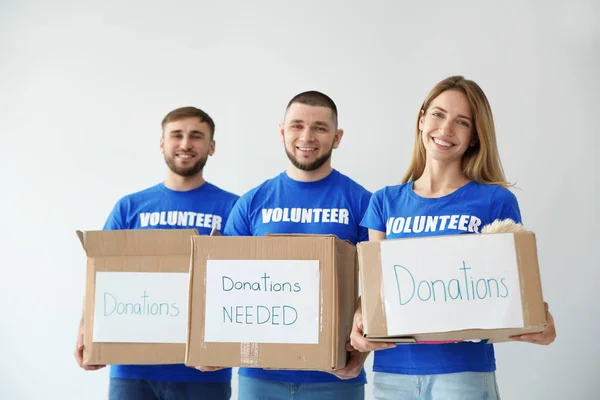 Jóvenes Voluntarios Sosteniendo Cajas Con Donaciones Para Pobres Sobre Fondo — Foto de Stock