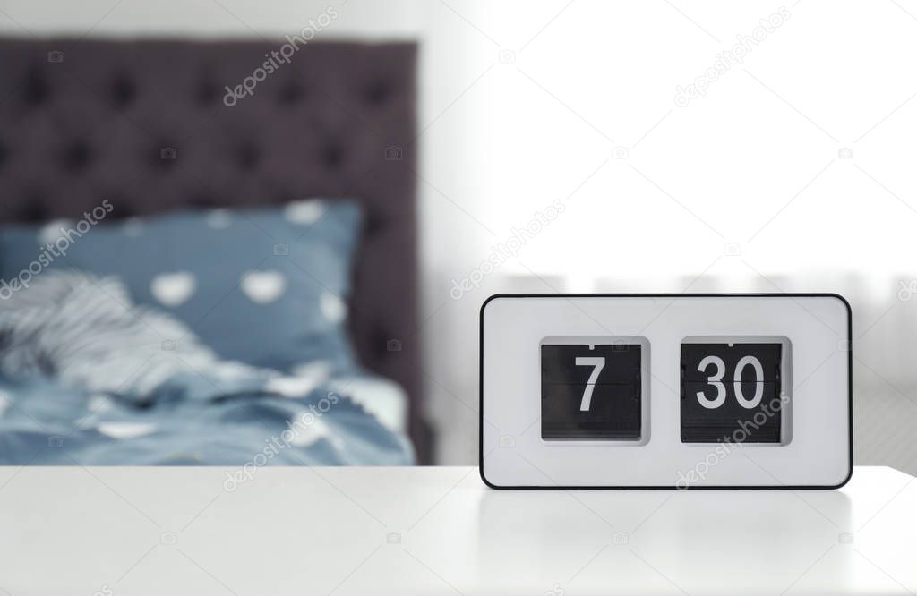 Digital alarm clock on table in bedroom. Time of day