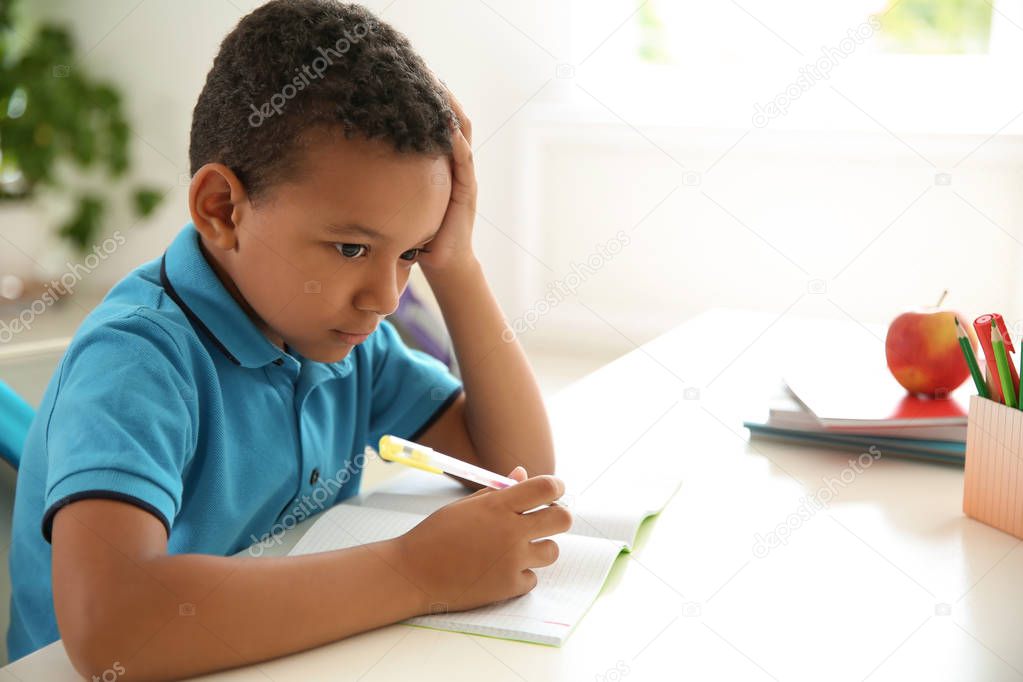 Cute little child doing assignment at desk in classroom. Elementary school