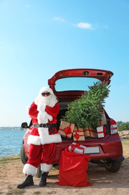 Otantik Noel Baba hediye kutuları ve Noel ağacı sahilde kırmızı araba yakınındaki
