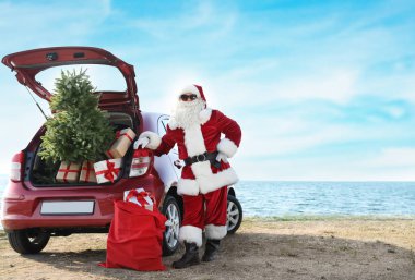 Otantik Noel Baba hediye kutuları ve Noel ağacı sahilde kırmızı araba yakınındaki