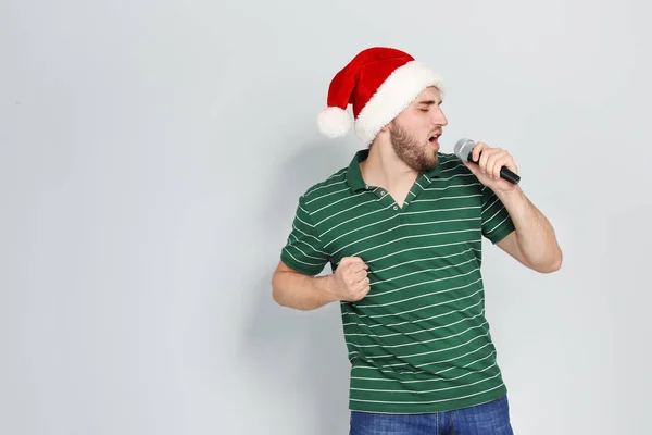 Молода Людина Санта Капелюсі Співає Мікрофоні Кольоровому Фоні Різдвяна Музика — стокове фото
