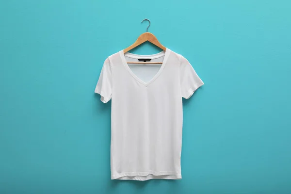 Hanger with blank t-shirt on color background. Mockup for design