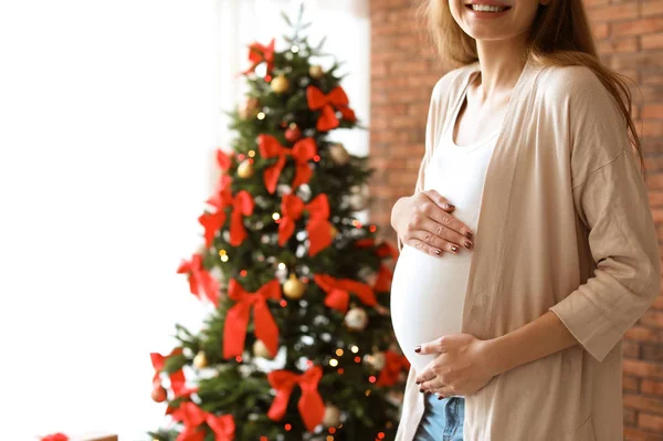 妊娠中の女性は 自宅のクリスマス ツリーの近く 赤ちゃんを期待してください — ストック写真