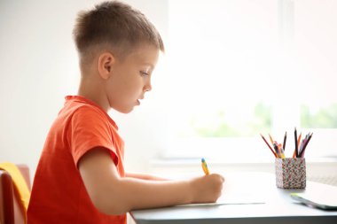 Sevimli küçük çocuk sınıfta masasında atama yapıyor. İlköğretim Okulu