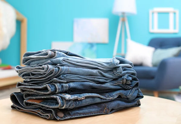 Pilha Jeans Elegantes Mesa Contra Fundo Desfocado — Fotografia de Stock
