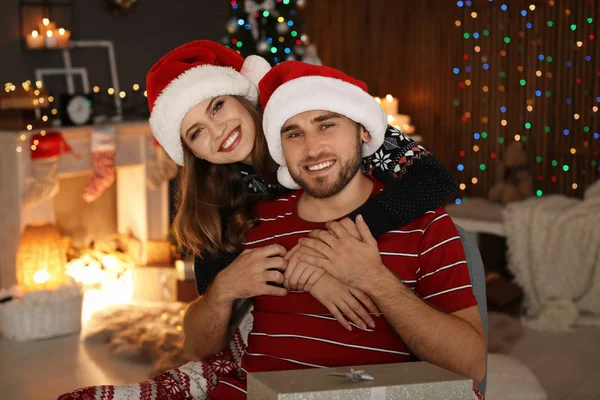 快乐的年轻夫妇在圣诞老人的帽子庆祝圣诞节在家里 — 图库照片