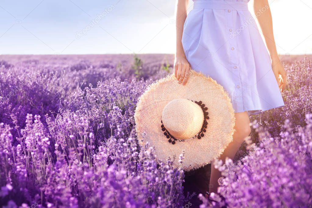 Young woman with hat in lavender field on summer day, closeup