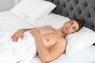 Genç adam yatağında uyuyor.