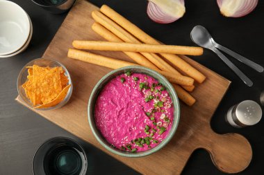 Düz kase lezzetli pancar ile kompozisyon Humus, cips ve ekmek sopa koyu arka plan üzerinde yatıyordu.