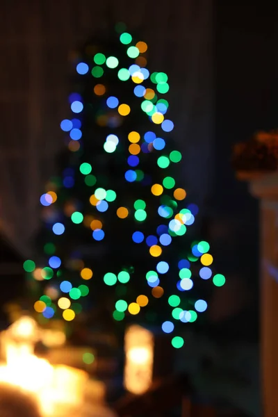 Blurred view of stylish living room interior with Christmas tree and fairy lights at night