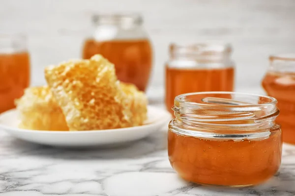 大理石のテーブルの上に甘い蜂蜜が付いているガラス瓶 — ストック写真