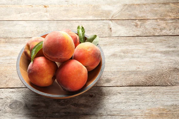 Plate with fresh sweet peaches on wooden table