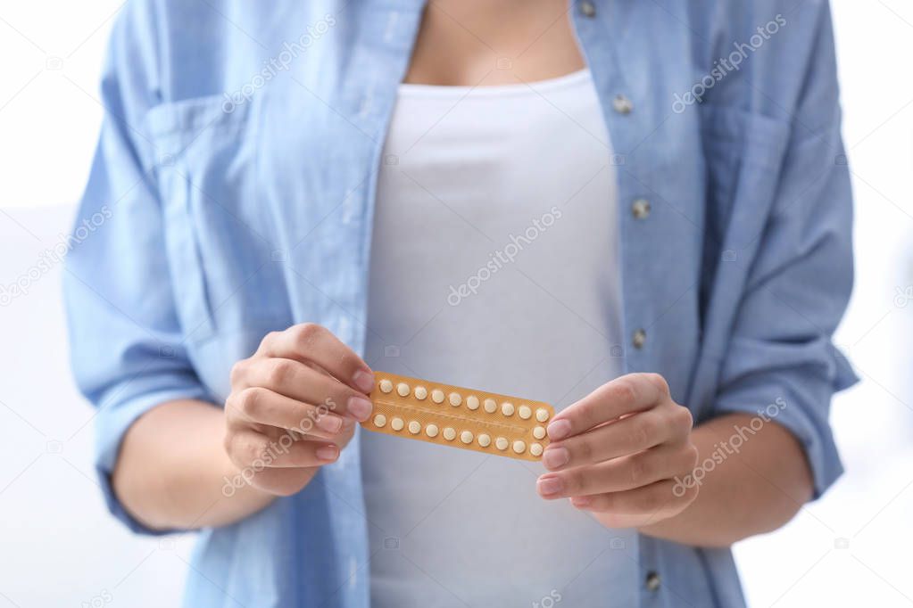 Young woman with birth control pills on light background. Gynecology