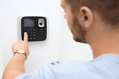 Genç adam kapalı alarm sistemi tuş takımında kodunu girme