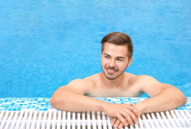Yüzme havuzunda ferahlatıcı suyla yakışıklı genç bir adam.