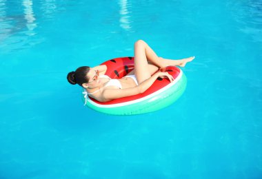 Yüzme havuzunda şişme halkası üzerinde bikini giyen güzel genç kadın