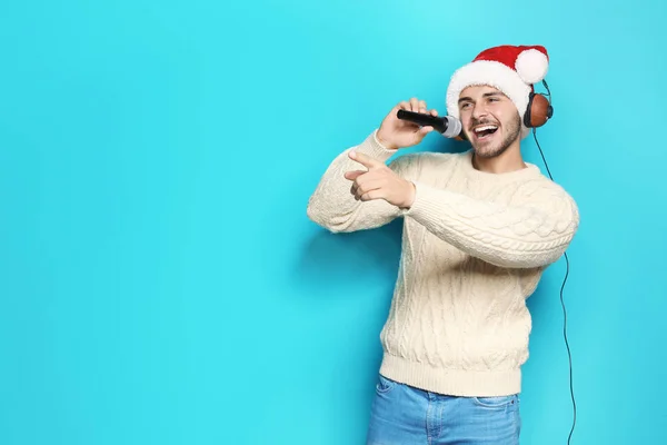 Santa Şapka Şarkı Renk Arka Plan Üzerinde Mikrofon Içine Genç — Stok fotoğraf