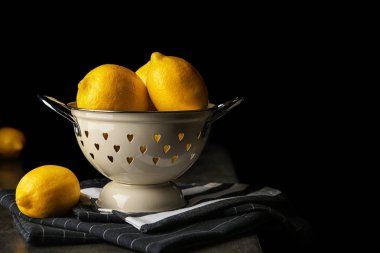 Kevgir koyu arka plan karşı masadaki bütün limon ile