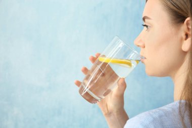 Genç kadın içme suyu limon rengi arka plan