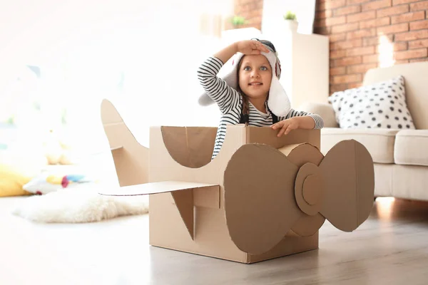Adorable little child playing with cardboard plane at home