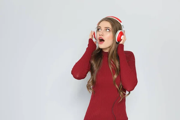 色の背景上のクリスマス音楽を聴く若い女性 — ストック写真