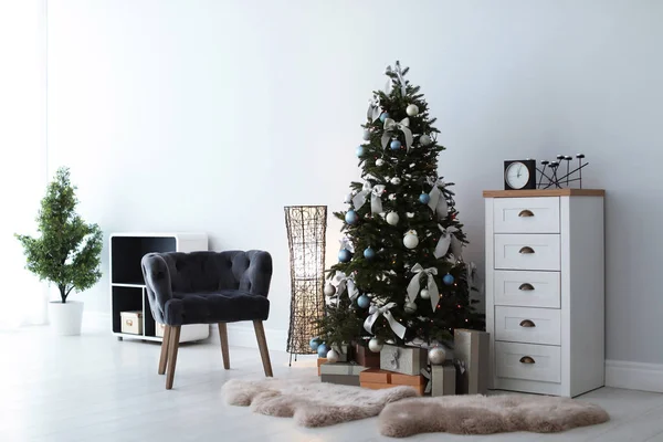 Stylish living room interior with decorated Christmas tree and comfortable armchair