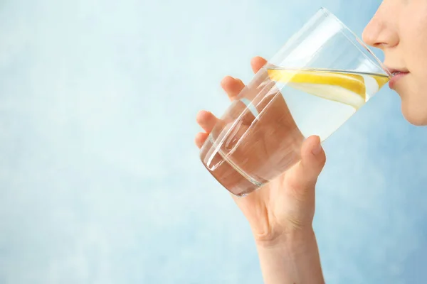 Mujer Joven Bebiendo Agua Con Limón Sobre Fondo Color —  Fotos de Stock