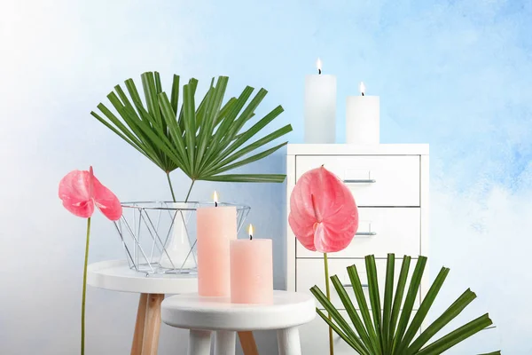 Creative composition with candles and tropical plants indoors
