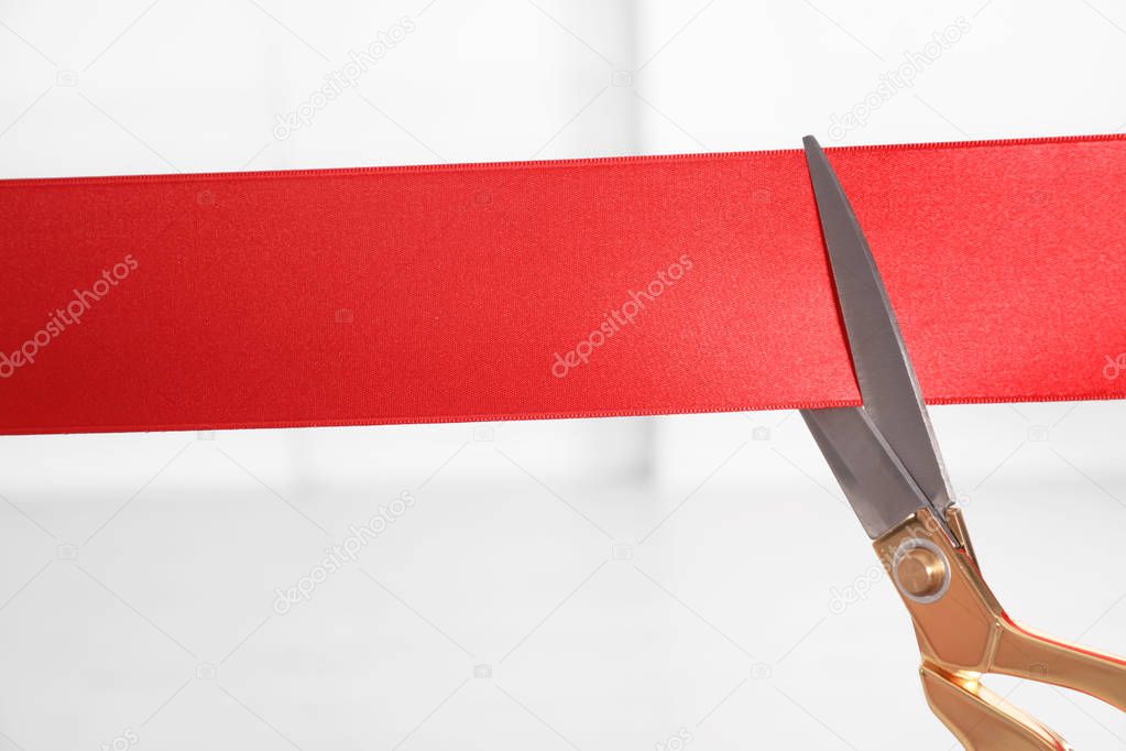 Ribbon and scissors on blurred background. Ceremonial red tape cutting