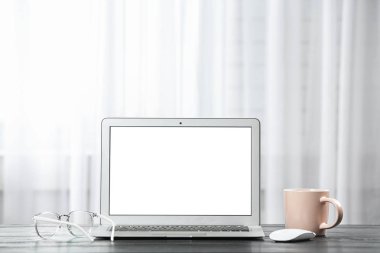 Ofisteki pencerenin yanındaki masada dizüstü bilgisayar. Rahat bir iş yeri