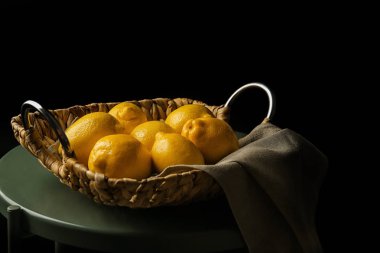 Küçük tablo karşı koyu arka plan üzerinde bütün limon ile sepeti