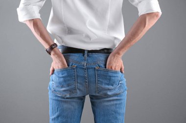 Adam gri arka plan üzerinde şık mavi jeans