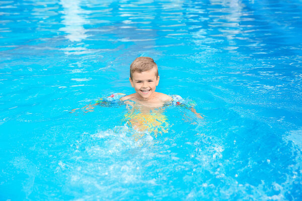 Маленький мальчик в бассейне в солнечный день
