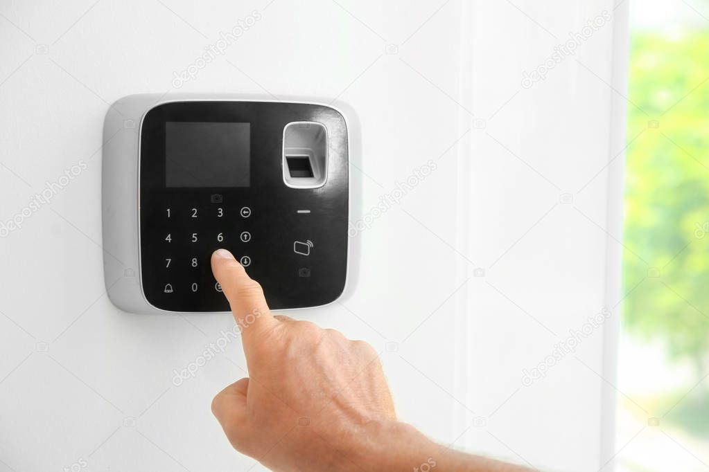 Mature man entering code on alarm system keypad indoors