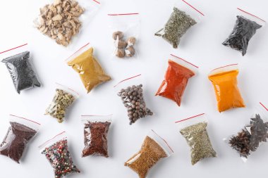 Beyaz arka planda, üstten görünüm farklı baharatlar ile plastik torbalar