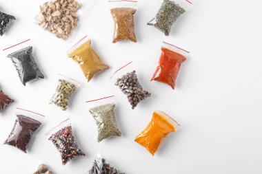 Beyaz arka planda, üstten görünüm farklı baharatlar ile plastik torbalar
