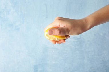 Genç kadın renk arka plan üzerine limon sıkarak