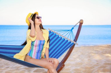 Sahil, hamakta oturan bir genç bayan. Yaz tatili