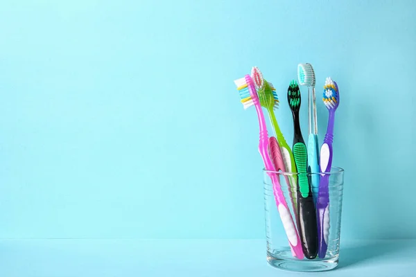 Cup with toothbrushes on color background. Dental care