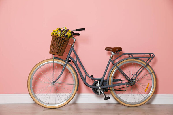 Retro bicycle with wicker basket near color wall