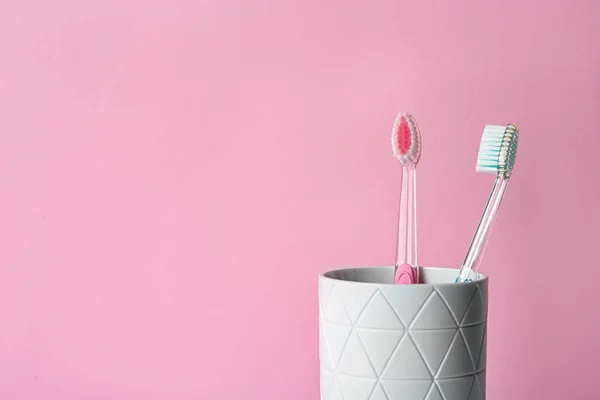 Tasse Mit Zahnbürsten Vor Farbigem Hintergrund — Stockfoto