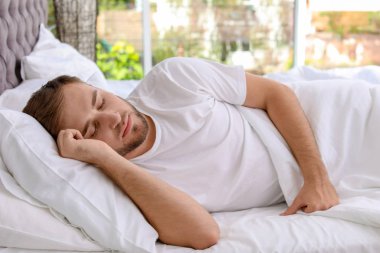 Evde yatakta uyuyan yakışıklı delikanlı. Sabah erken