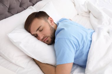 Evde yatakta uyuyan yakışıklı delikanlı. Sabah erken