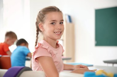 Sınıfta masada oturan sevimli küçük çocuk. İlköğretim Okulu