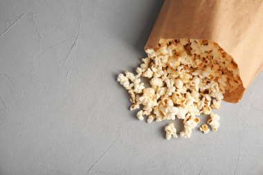 Kağıt torba gri arka plan, üstten görünüm üzerinde lezzetli patlamış mısır ile