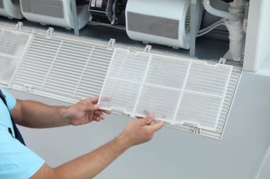 Erkek teknisyen içeride klimayı temizliyor.