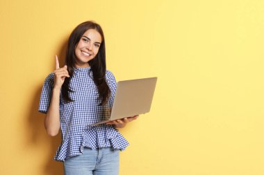 Renk arka plan üzerinde modern dizüstü bilgisayar ile genç kadın
