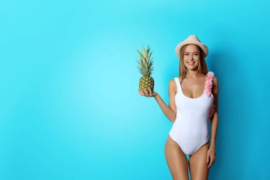 Renk arka plan üzerinde ananas ile bikinili seksi genç kadın